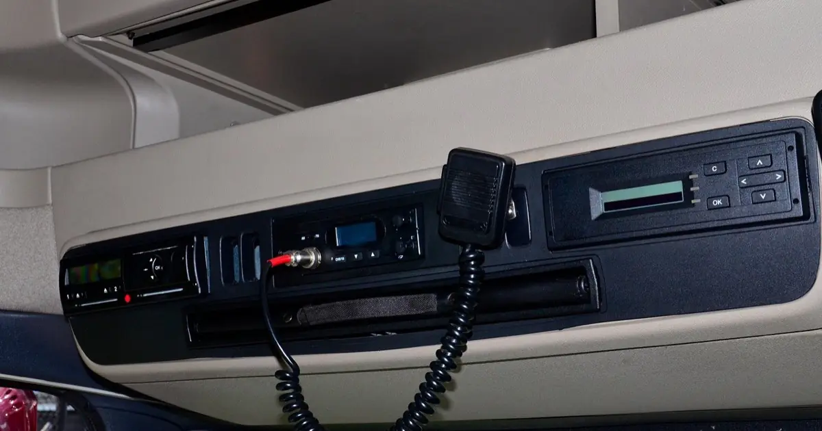 Cabine de caminhão com o tacógrafo instalado no painel superior, ao lado do rádio comunicador